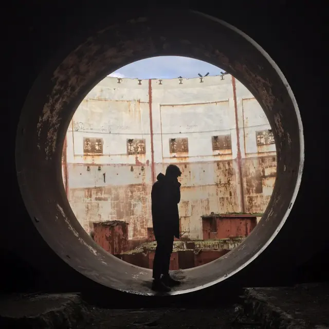 Alexey silhouetted inside a circular industrial opening