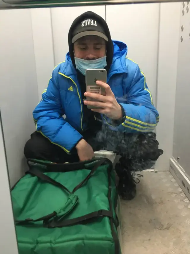 Alexey taking a mirror portrait in a blue jacket and face mask