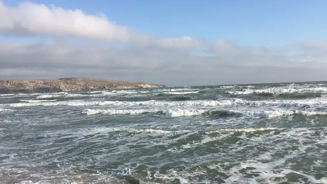 Waves breaking under a cloudy sky