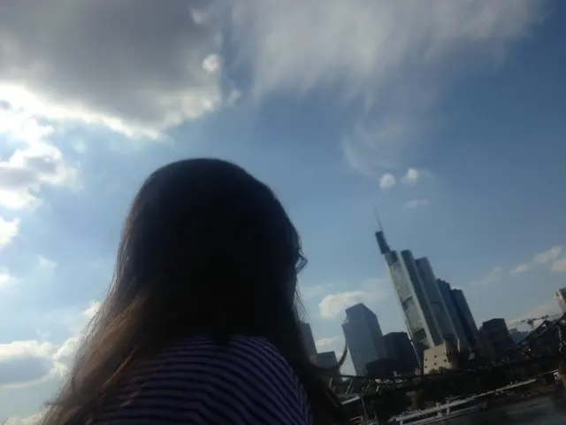 A woman by the water with a city skyline beyond
