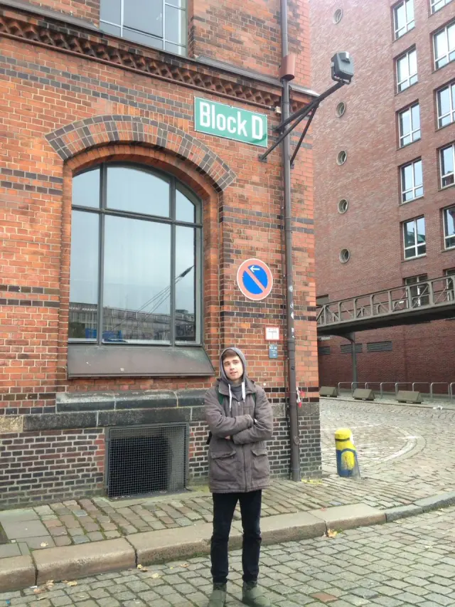 Alexey outside a brick building with a bar sign