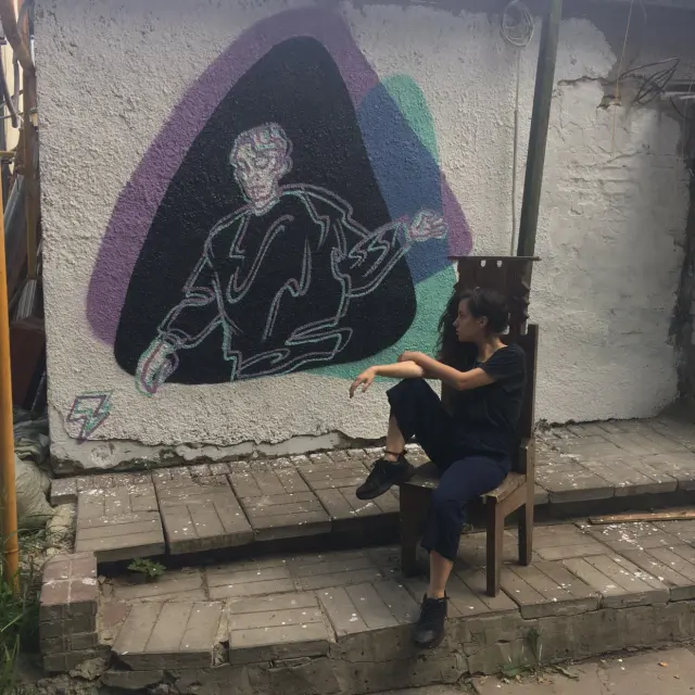 A seated person beneath a painted mural