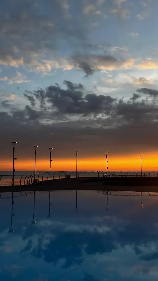 An orange sunset reflected in a pool