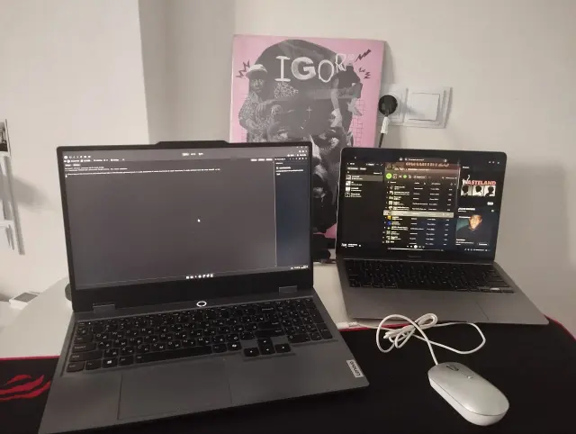 Two laptops, a mouse and earphones on a desk